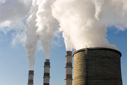 Close-up of the top of factories' chimneys releasing white smoke. 